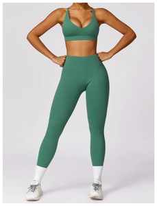 Detail view of high-waist yoga leggings and V-neck sports bra in dark green fabric