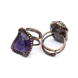 Close-up of vintage bronze rings with raw amethyst geodes and detailed wire wrap texture