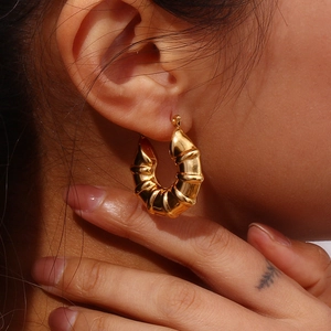 Close-up of 18K gold plated croissant style hoop earrings worn by a model