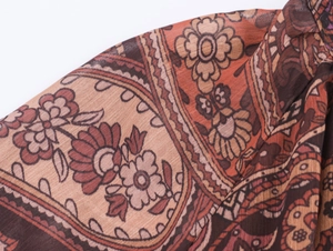 Macro view of reddish-brown paisley and floral print on breathable lightweight fabric