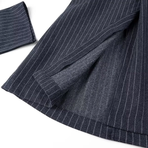 Dettaglio del cappotto pesante in lana grigio scuro a righe che mostra il tessuto e l'interno