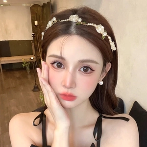 Close-up of white roses and pearls headband worn by a model in soft lighting