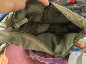Detail view of the green nylon crossbody bag interior with zipper pocket and lining