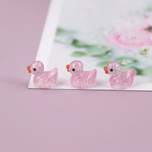 Close-up of three pink glitter resin miniature ducks for DIY landscape decoration
