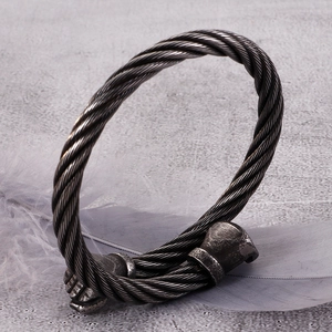 Detail of vintage twisted cable stainless steel bangle on a soft grey feather