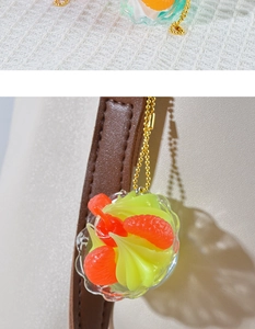 Close-up of a mini lemon sundae keychain with a red cherry on a brown leather handle