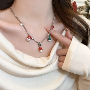 Detailed view of Christmas necklace with red green enamel charms and pearls on a model