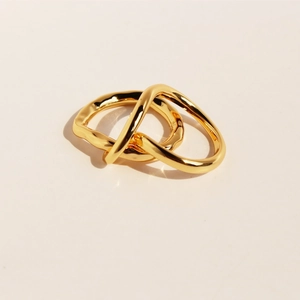 Interlocking twisted double band ring in gold plated brass with minimalist aesthetic