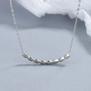 Primer plano del collar de plata de ley con colgante de cuentas curvadas y cadena fina