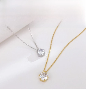 Detail of minimalist necklaces with six-prong set zircons in gold and silver finishes