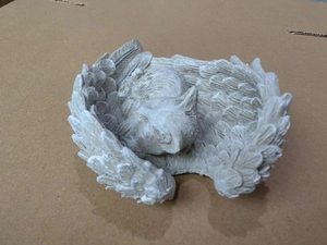 Detailed view of a sleeping pet resin memorial statue nestled in angel wings