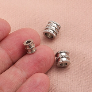Perles en acier inoxydable maillé pour bijoux DIY montrées avec main pour l'échelle