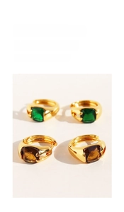 Detail of square emerald and amber zircon stones set in gold polished hoop earrings