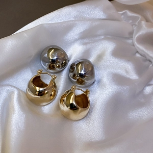 Detail of gold and silver metallic round hoop earrings on a white silk background