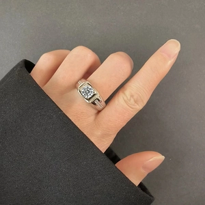 Detailed view of a silver square-cut moissanite ring with side stones on finger