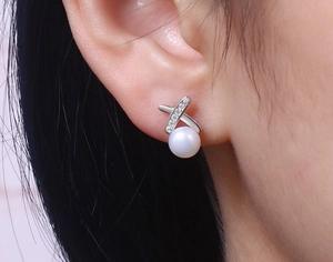 Detail of S925 silver pearl stud earrings featuring a crossed X-shape and micro-inlaid zircons