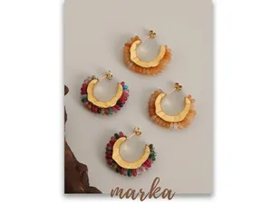 Detailed shot of C-shaped gold earrings with colorful natural stone beads on stone texture