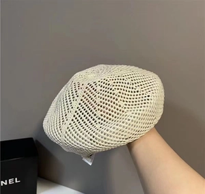 Detail of a beige hollow crochet beret hat with breathable mesh texture and white tag