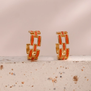 Detail of gold geometric hollow chain earrings with vibrant orange enamel inlay finish