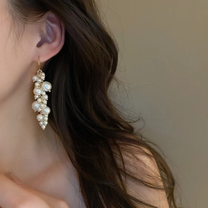 Detail view of elegant French vintage pearl tassel earrings on a model's ear