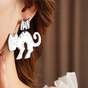 Close-up of white crown cat earrings with black outlines worn on a model's ear