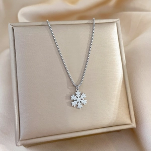Detail of silver snowflake pendant on a box chain resting on a premium jewelry box
