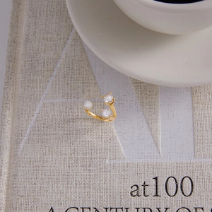 Detail of adjustable gold ring with three white zircons on a book page with coffee cup