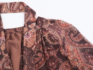 Detail of bohemian paisley print dress featuring deep v-neck and pleated halter neck style