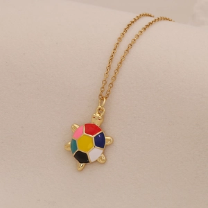 Detail of a gold stainless steel turtle pendant with colorful enamel shell on a chain