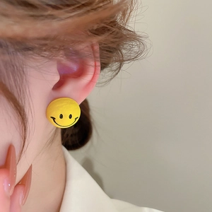 Detailed side view of a model wearing a cute yellow cartoon smiley face stud earring