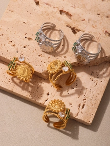 Detail of gold and silver sun rings with zircon cactus accents on a stone surface