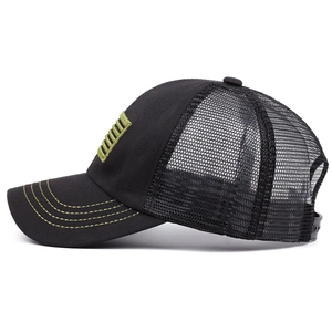 Close-up of black mesh trucker hat with green stitching and decorative side patch