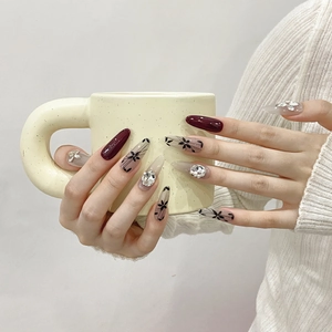 Handmade burgundy cherry press-on nails with floral hand-painted designs and rhinestones