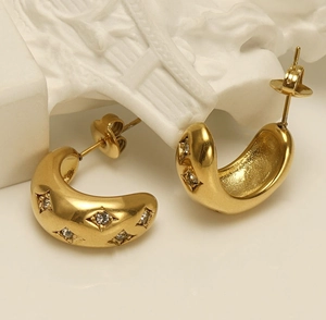 Vue macro de boucles d'oreilles C dorées avec des zircons sertis en forme d'étoile