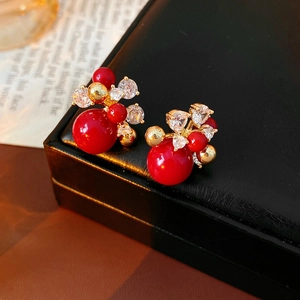 Macro shot of gold-plated berry-shaped earrings with red pearls and sparkling zircon