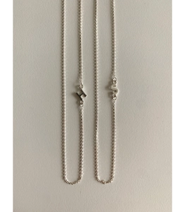 Macro detail of silver minimalist H and S letter pendants on delicate link chains