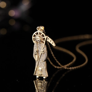 Pendentif Santa Muerte doré avec pierres de zircon sur une surface noire réfléchissante