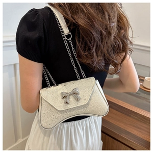 Close-up of white sequin shoulder bag with silver chain strap and metal bow detail