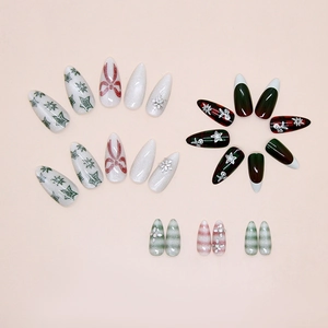 Detailed flat lay of Christmas press-on nails with snowflakes and green glitter patterns
