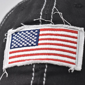Macro shot of embroidered USA flag patch and distressed cotton fabric on black baseball cap