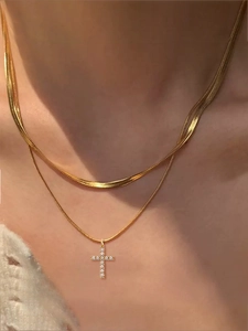 Close-up of double layer gold snake chain with sparkling cross pendant on a model