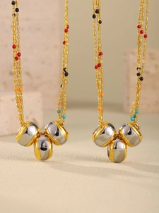 Detail of beaded gold chain necklace featuring multi-colored accents and cylindrical pendants