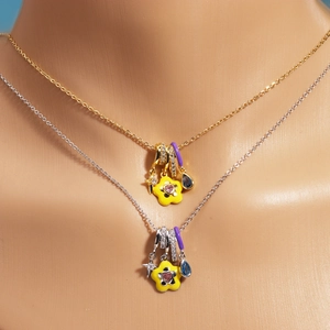 Close-up of stacked gold and silver necklaces with colorful floral and teardrop pendants
