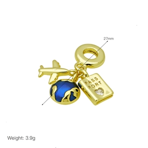 Macro detail of gold-plated travel pendants featuring globe, airplane, and passport charms