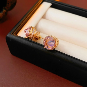 Macro shot of 18k gold plated earring with pink-purple gemstone and zircon halo detail