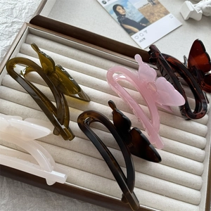 Detailed arrangement of butterfly hair claws in five colors on a velvet display tray
