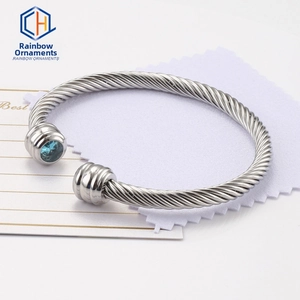 Close-up of silver twisted cable cuff bracelet featuring vibrant blue zircon stones