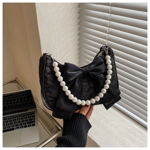 Detail of velvet bow and pearl handle on black textured mini shoulder bag for women