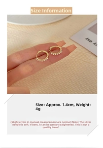 Close-up of 1.4cm gold pearl hoop earrings with silver needles on human hand