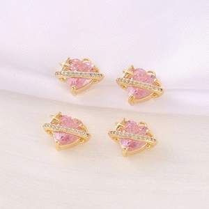 Makroansicht von vier rosa Herz-Planeten-Anhängern für DIY-Schmuck auf weißem Stoff